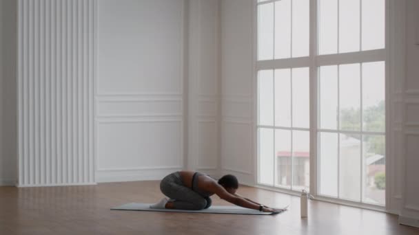 Giovane donna afroamericana sportiva che pratica yoga nella posa dei bambini - Filmati, video
