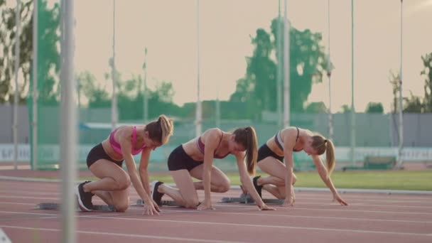 Tres mujeres atletas simultáneamente comienzan a correr maratón, rivalidad, cámara lenta. mujeres de pie en una línea de partida antes de la carrera - Metraje, vídeo