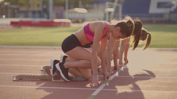 Drie vrouwelijke atleten gaan tegelijkertijd marathon lopen, rivaliteit, slow-motion. vrouwen die voor de race op een startlijn staan - Video