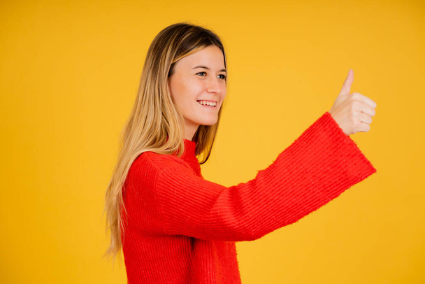 Young woman showing thumb up to someone. - Foto, afbeelding