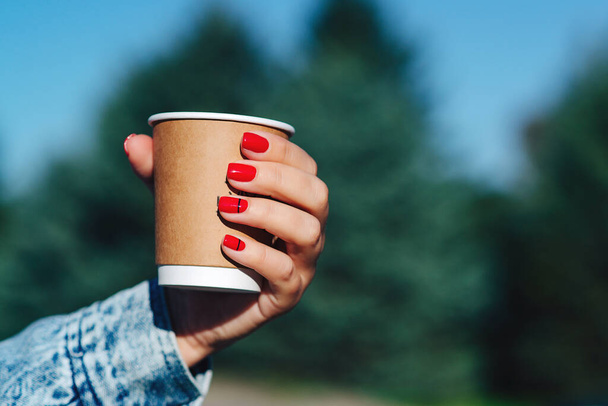 Paper coffee cup in woman hands with perfect manicure. Female hand with coffee take away. Woman holding cup in hands. Drinking take away coffee. - Photo, image