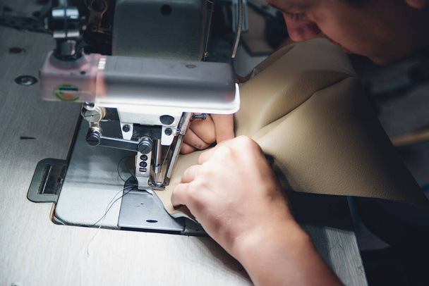 Processo de trabalho do artesão de couro. Tanner costura couro em uma máquina de costura especial, de perto. Produto de couro de costura do trabalhador na máquina de costura. Oficina de couro. - Foto, Imagem