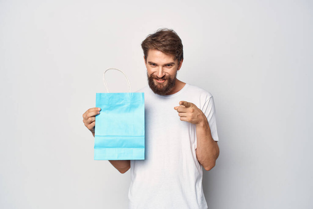 muž v bílém tričku modrý balíček nakupování světlo pozadí - Fotografie, Obrázek