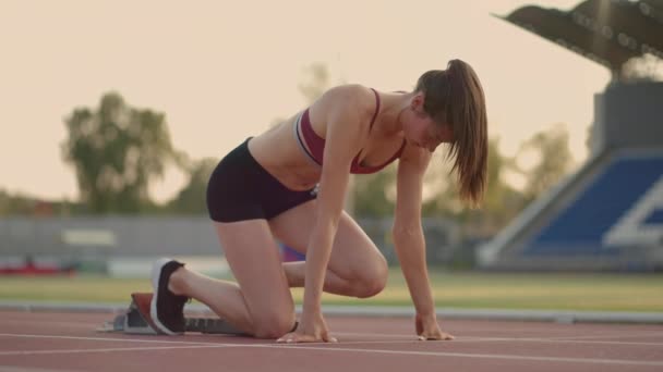 Caucasian young brunette woman shit for a run in the stadium comes up to the running sides and starts the sprint race in slow motion - Filmmaterial, Video