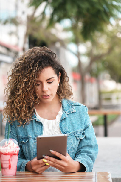 Latin woman using a digital tablet at a coffee shop outdoors. - Fotografie, Obrázek