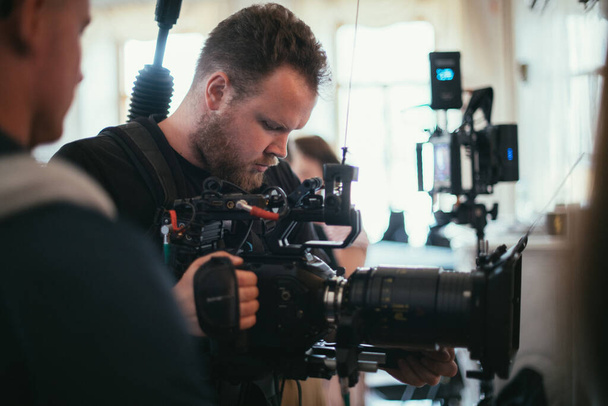 カメラを手に撮影監督が舞台に立つ。映画、商業、またはテレビシリーズの撮影の仕事でプロのビデオ撮影者。撮影プロセス室内、スタジオ - 写真・画像