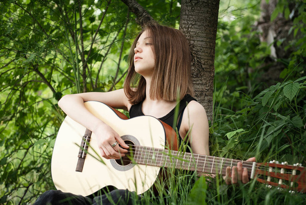 Teini tyttö soittaa kitaraa puistossa - Valokuva, kuva