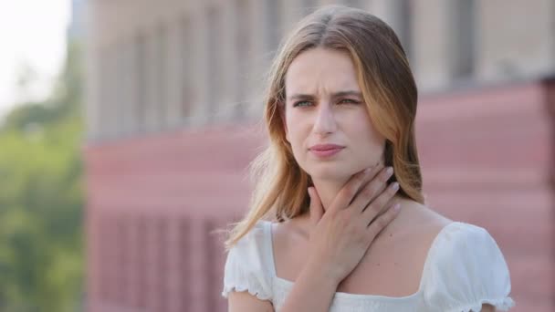 Tonsillitida angina koncept venkovní portrét na moderním stavebním pozadí nezdravá žena dotykový krk cítí nepříjemný pocit těžké polykat, bolest v krku podráždění nebo ztráta hlasu - Záběry, video