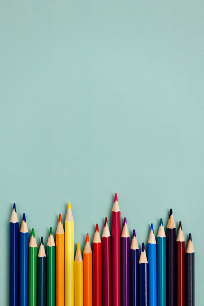 Kolorowe naostrzone ołówki leżą na niebieskim tle z miejscem do kopiowania. Artykuły szkolne lub przygotowanie do szkoły. - Zdjęcie, obraz