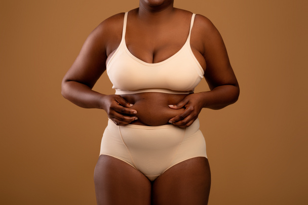 Zakrzywione Afroamerykanka kobieta w bieliźnie gospodarstwa Fat fałdy - Zdjęcie, obraz