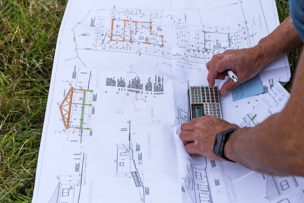 建設現場で家のための家の計画を持つハンディマン-クローズアップ - 写真・画像