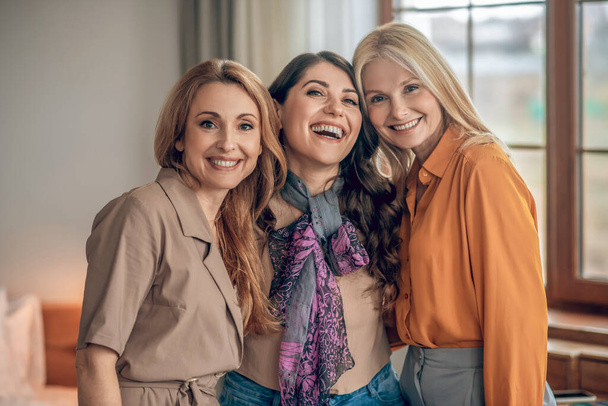 Three females in elegant outfits smiling and looking happy - Photo, image