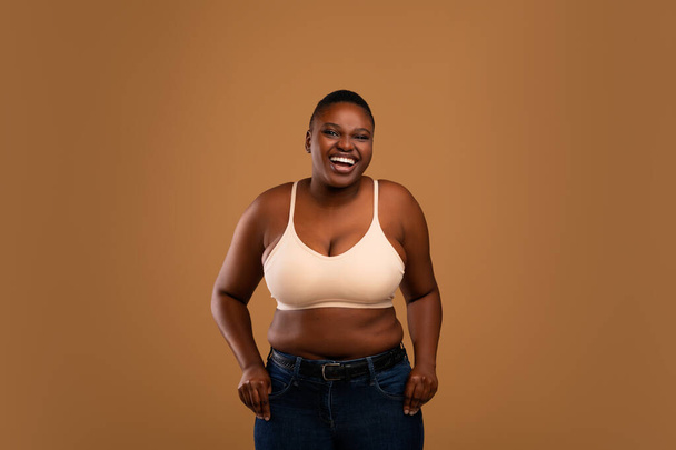 Portrait of casual young black woman laughing, brown wall - Photo, Image