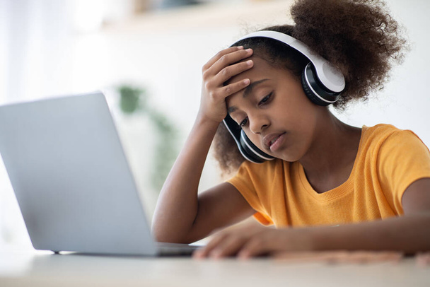 Yorgun siyah kız dizüstü bilgisayarın önünde oturuyor. - Fotoğraf, Görsel