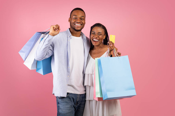 Portrait of happy afro couple holding credit card and bags - Photo, image