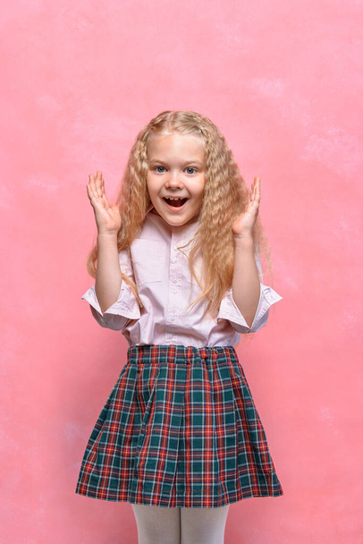 surprised little girl. emotion delight. schoolgirl in uniform. pink background - 写真・画像