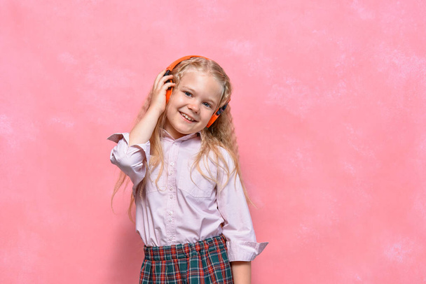 portrait of little girl in headphones. schoolgirl in uniform. pink background - Fotoğraf, Görsel