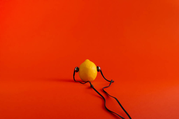 Шматок лимона, який насолоджується музикою або тишею на червоному тлі
. - Фото, зображення