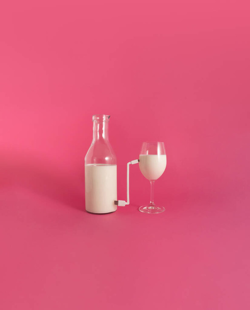 Бутылка с напитком, соединенная зарядным устройством с полным стаканом, на розовом фоне. - Фото, изображение