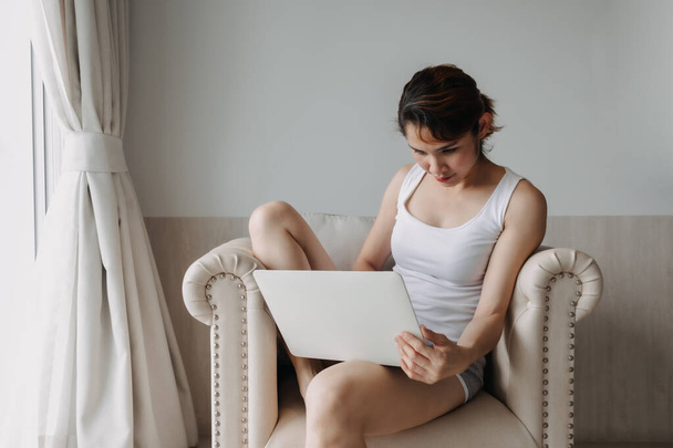 Woman works and relax with laptop on the sofa. Concept of work from hotel. - Photo, image