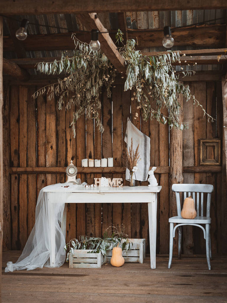 Hangulatos rusztikus terasz a régi vidéki ház a faluban. Fehér antik asztal dekoratív fa szó HOME mellett szék sárga tök rajta az őszi szezonban és a teljes betakarítás - Fotó, kép
