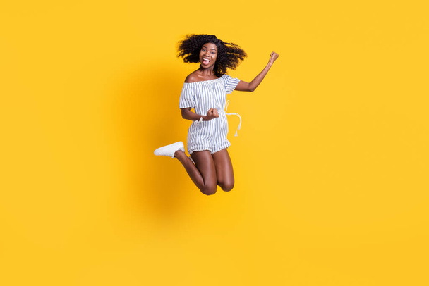 Full length body size view of attractive cheerful ecstatic fit girl jumping having fun rejoicing isolated over bright yellow color background - Foto, Imagen