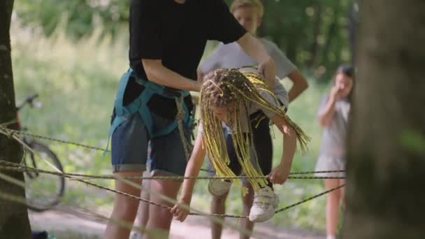 V letním táboře se má dcera učí překonávat lanové překážky a horolezectví. Učit děti o turistice a turistice - Záběry, video