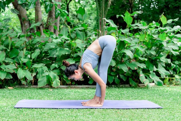 Aziatische aantrekkelijke jonge vrouw hebben een mooi lichaam, spelen yoga in een elegante houding, in het groene park, concept om mensen recreatie en gezondheidszorg concept. - Foto, afbeelding