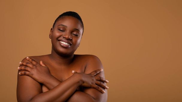 Portrait of beautiful plus size black woman hugging herself - Photo, Image