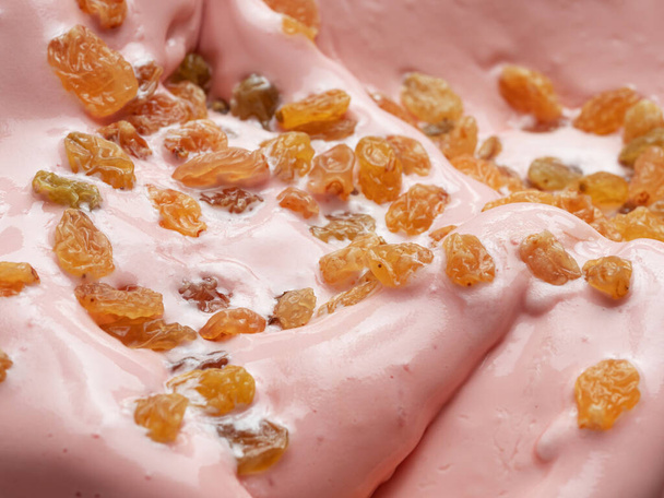 Punch flavour gelato - full frame detail. Close up of pink surface texture of Ice cream covered with pieces of raisins. - Fotografie, Obrázek