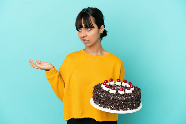 Giovane donna di razza mista in possesso di torta di compleanno in possesso di copyspace con dubbi - Foto, immagini