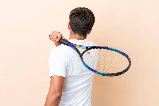 Jeune homme caucasien isolé sur fond ocre jouer au tennis - Photo, image