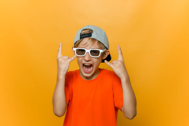 дитина в шапці і окулярах для перегляду фільмів показує важкі металеві жести і голосно кричить
 - Фото, зображення
