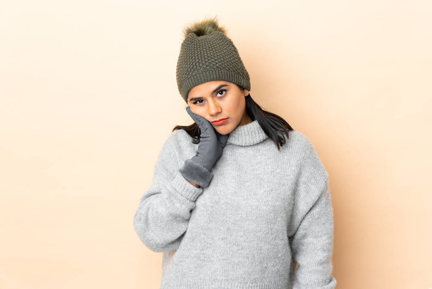 Young Colombian girl with winter hat isolated on beige background unhappy and frustrated - Foto, Bild