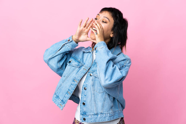 Young Uruguayan woman over isolated pink background shouting and announcing something - Foto, afbeelding