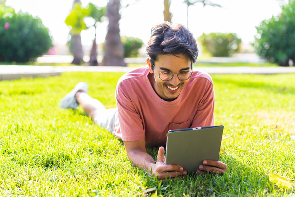 Young caucasian man at outdoors in a park holding a tablet - Photo, image