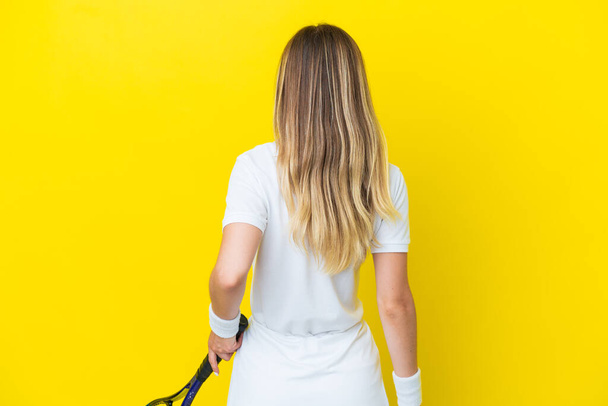 Giovane donna rumena isolata su sfondo giallo giocare a tennis - Foto, immagini