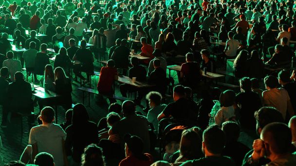Pessoas sentadas assistindo futebol em um lugar público à noite - Foto, Imagem
