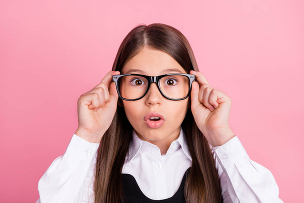 Fénykép a meglepett megdöbbent kislány visel szemüveg szemüveg látás iskoláslány elszigetelt rózsaszín színű háttér - Fotó, kép