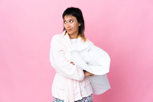 Young Uruguayan woman in pajamas over isolated pink background thinking an idea - Photo, Image
