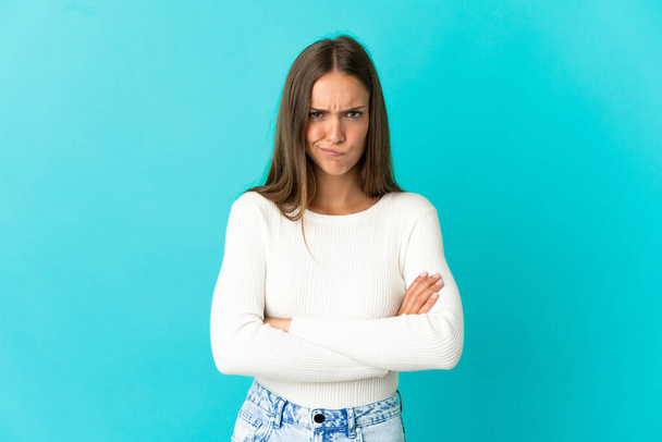 Νεαρή γυναίκα πάνω από απομονωμένο μπλε φόντο με δυστυχισμένη έκφραση - Φωτογραφία, εικόνα