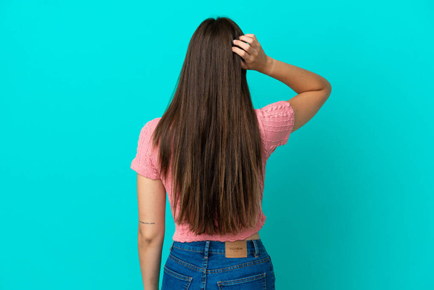 Fiatal brazil nő elszigetelt kék háttérrel hátsó pozícióban és gondolkodás - Fotó, kép