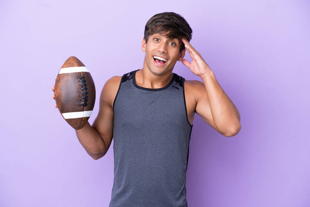 Young man playing rugby isolated on purple background with surprise expression - Photo, Image