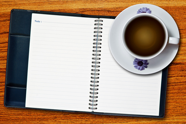 bílý šálek kávy a prázdné stránky poznámkového bloku na dřevěné tabulce pozadí - Fotografie, Obrázek