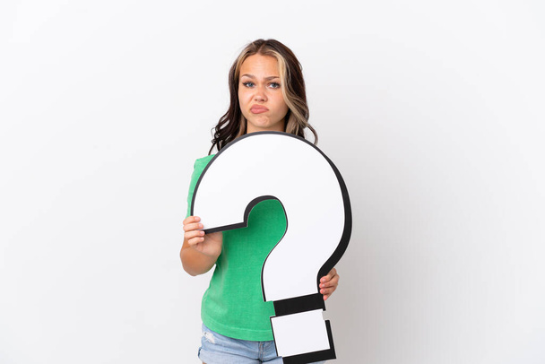 Teenager Russian girl isolated on blue background holding a question mark icon and with sad expression - Foto, Imagem
