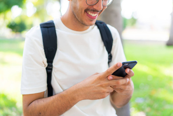 Jeune étudiant homme à l'extérieur en utilisant un téléphone mobile - Photo, image