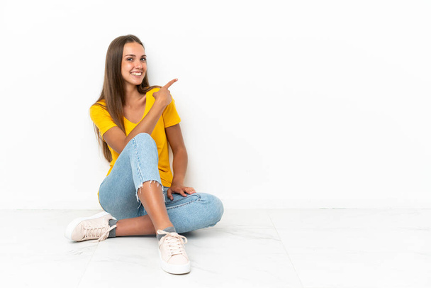 Young girl sitting on the floor pointing back - Foto, imagen