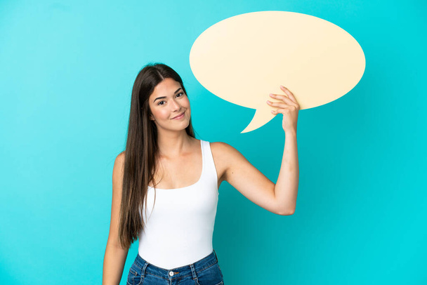 Young Brazilian woman isolated on blue background holding an empty speech bubble - Photo, Image