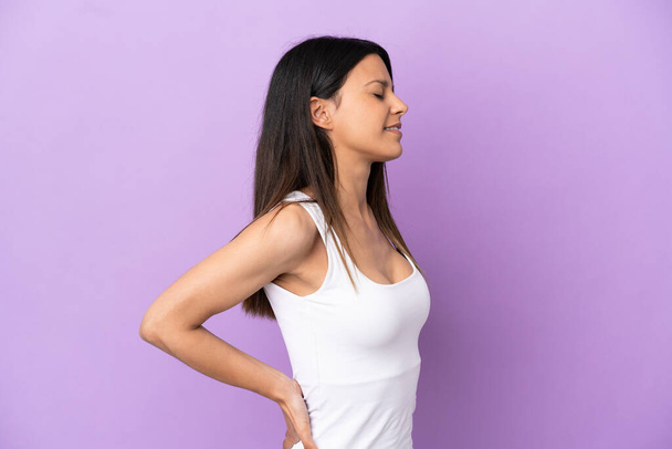 Nuori valkoihoinen nainen eristetty violetti tausta kärsii selkäkipu on tehnyt vaivaa - Valokuva, kuva