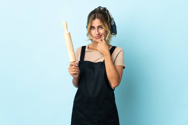 Junge blonde uruguayische Köchin isoliert auf blauem Hintergrund denken - Foto, Bild